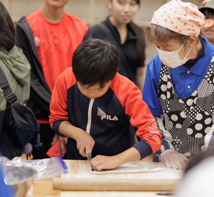 子供が料理するところをすぐそばで見守る女性