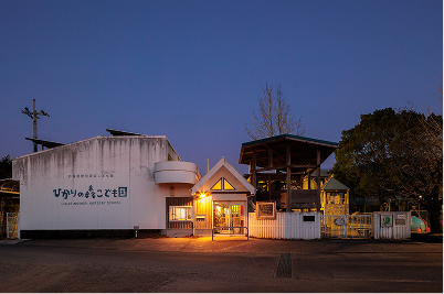 正面の白い壁に「ひかりの森こども園」と書かれたひかりの森こども館